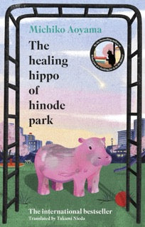 Book cover of 'The Healing Hippo of Hinode Park' by Michiko Aoyama with a pink hippo illustration.