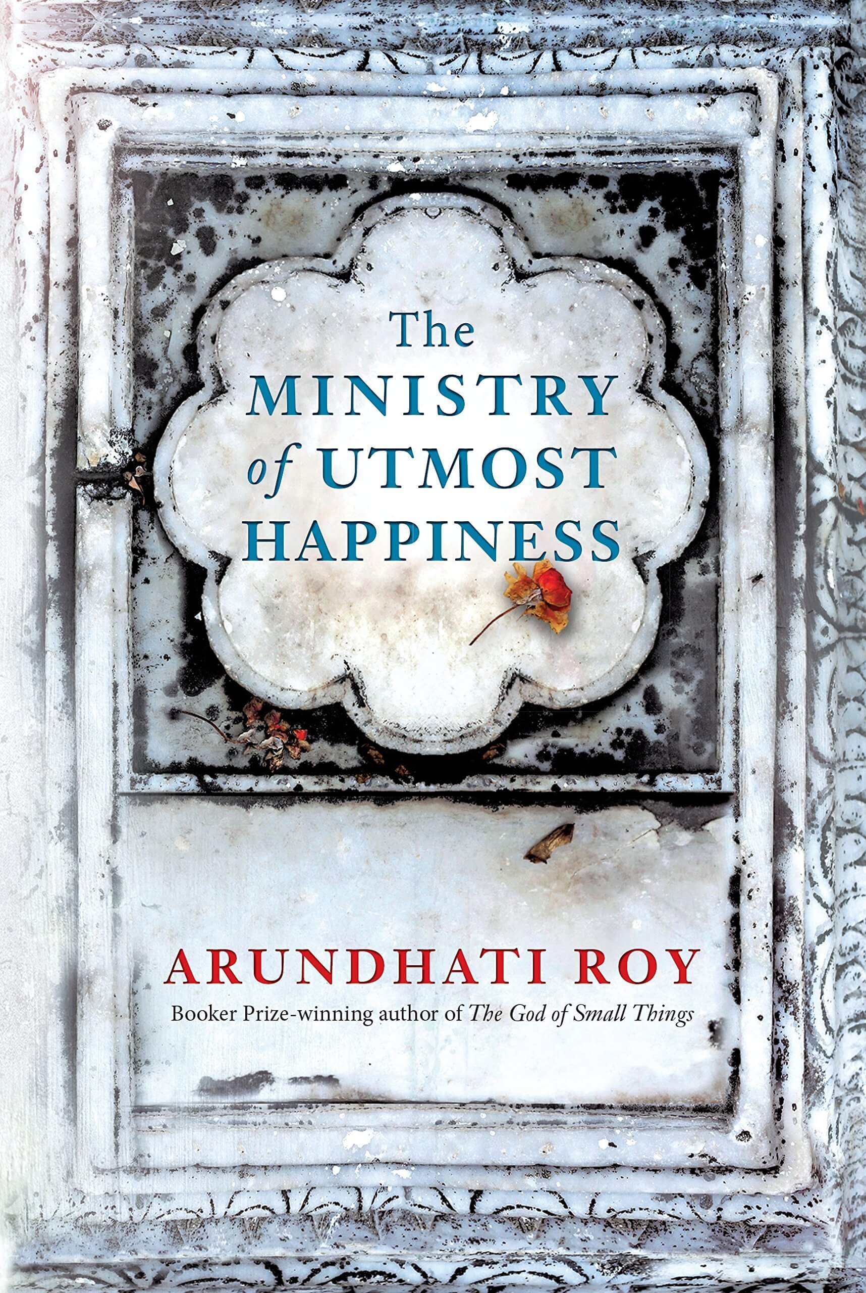 The image shows the cover of the book 'The Ministry of Utmost Happiness' by Arundhati Roy. The cover features a textured, old-worldly background with a large, ornate, gray doorway-like structure.